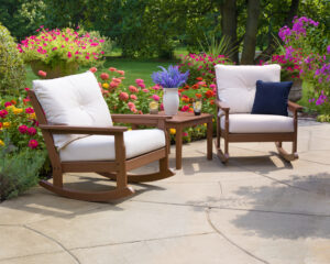 eco-friendly brown outdoor rocker with white cushion in a colorful garden