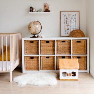 kids room with crib, white shelves, rattan baskets, doll house, and fuzzy white rug