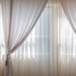 two sets of beige curtains covering windoe