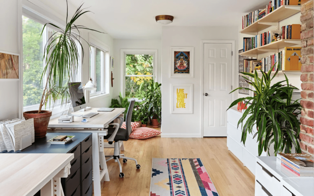 Holistically designed office space with white walls, computer desk, and bright colored art and rug.