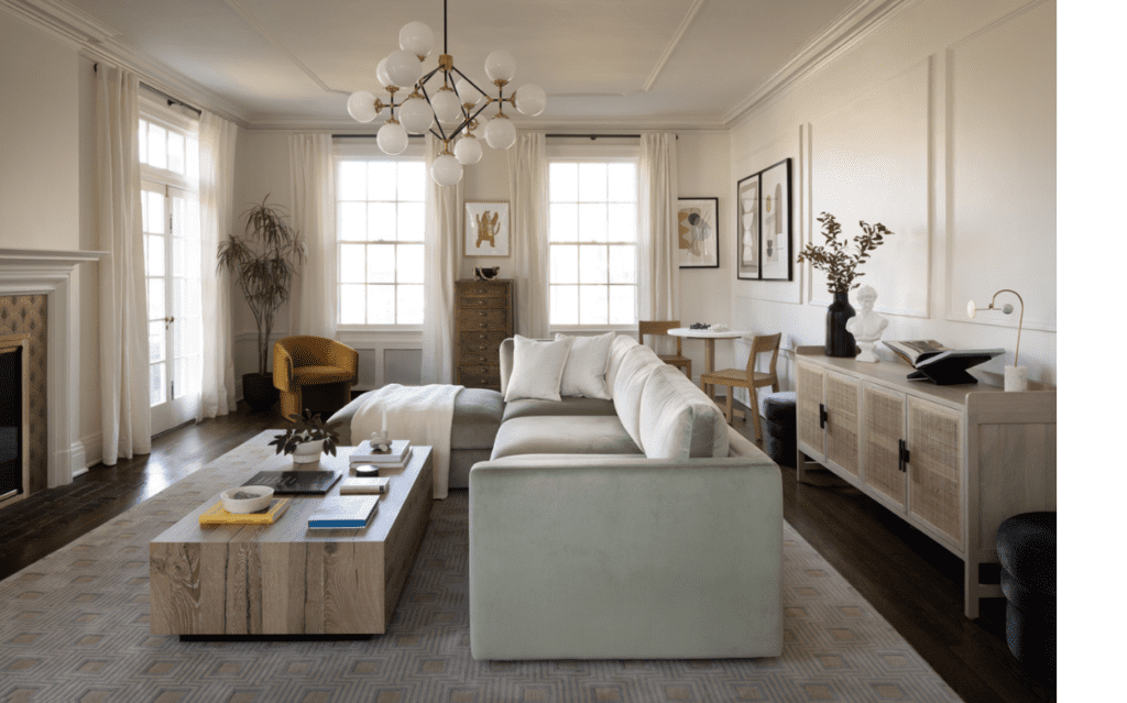 holistically designed living room with cream walls, sputnik chandalier, sage colored sofa and wood tables.