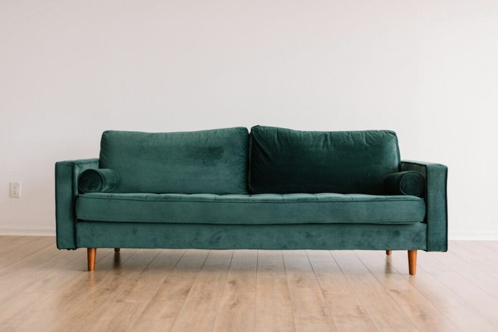 green sofa in room with light wood floors and white walls